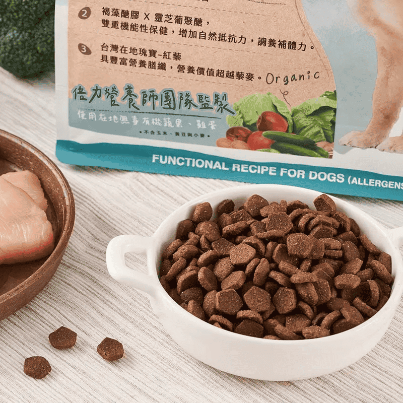 倍力狗飼料顆粒飽滿，搭配飼料袋上的有機蔬果圖案與生雞肉塊，展現產品的天然食材與豐富營養。